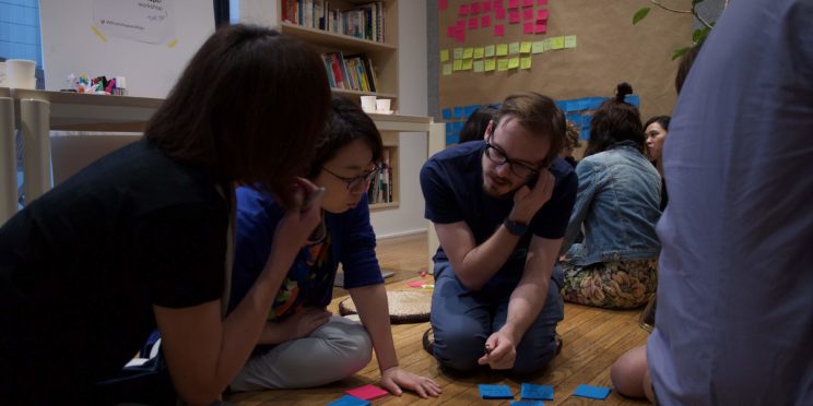 A group of people sitting on the floor looking at post-it notes