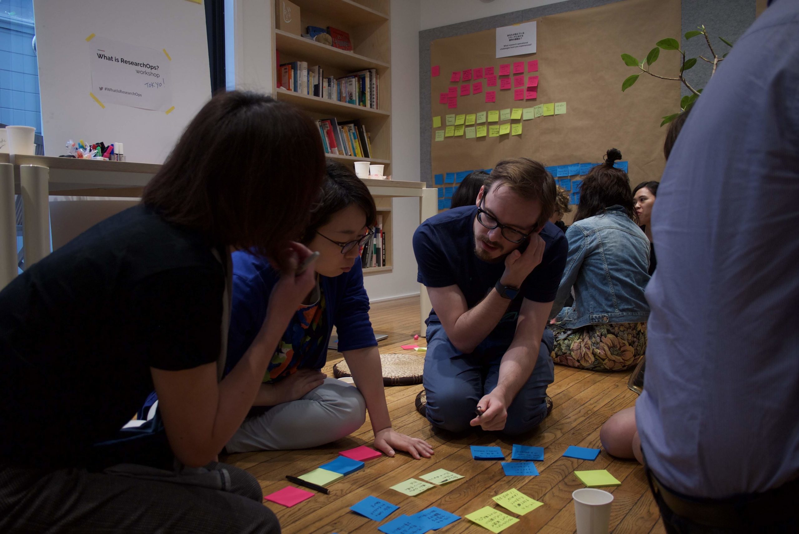 A group of people sitting on the floor looking at post-it notes