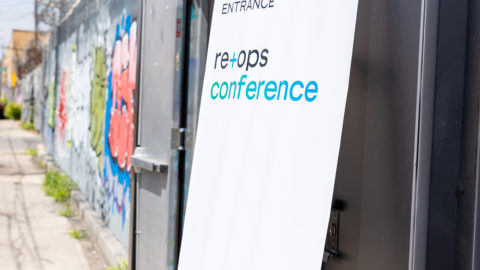 A welcome banner outside the ReOps22 venue next to graffiti on the wall, the sign says Entrance ReOps Conference