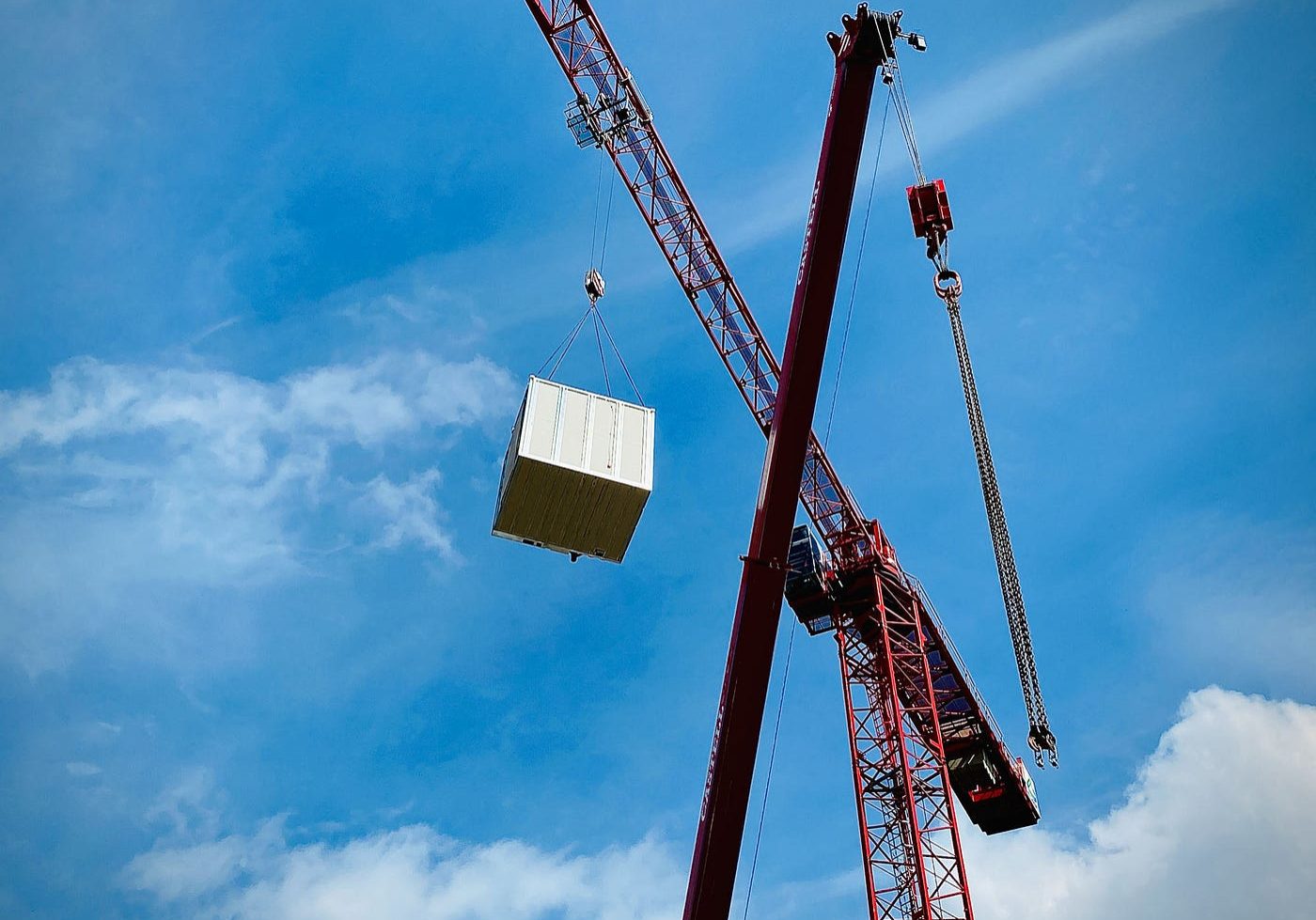 Crane picking up a large container with a blue sky behind it